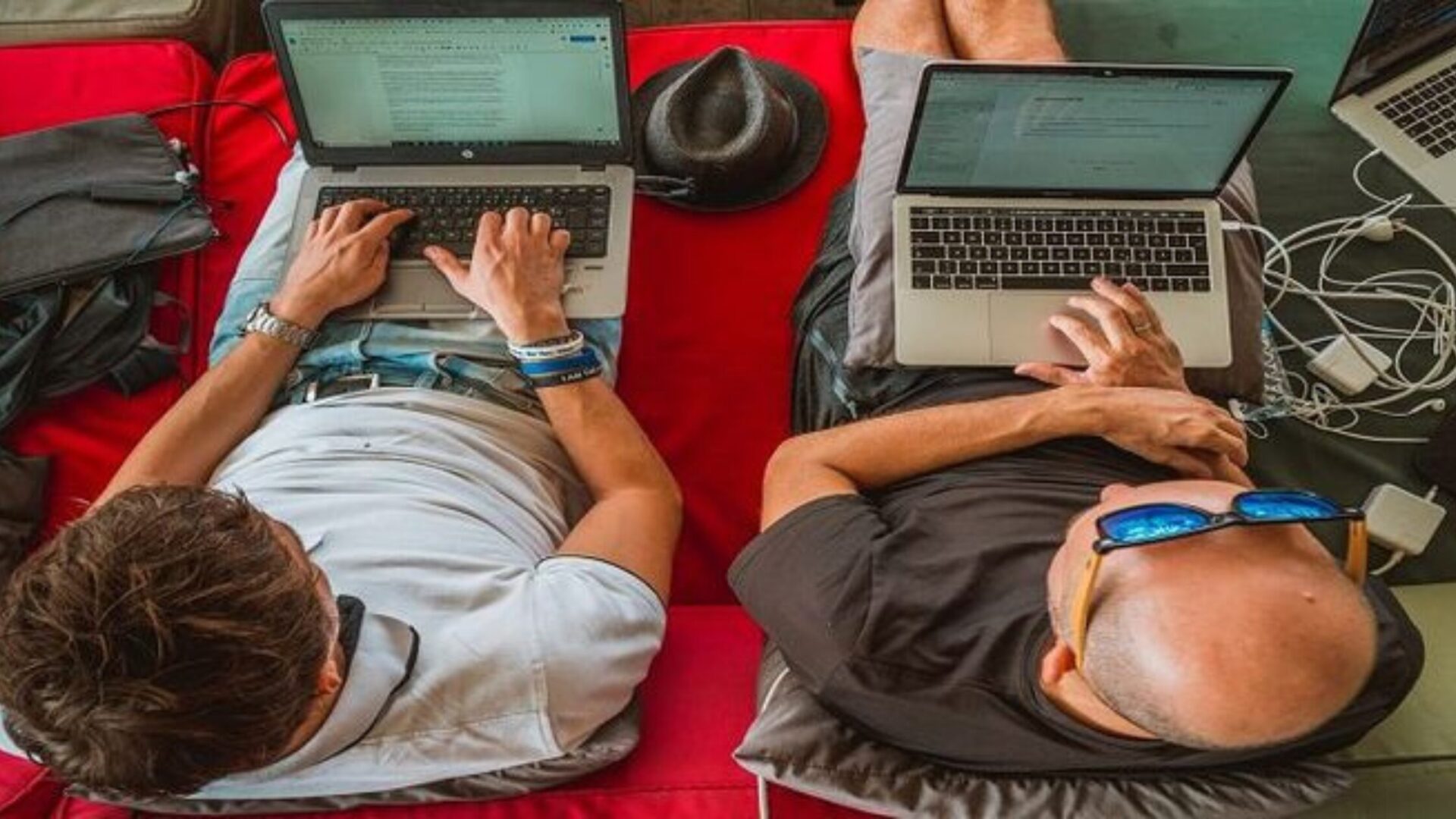 Two men sitting on a couch with laptops, exemplifying remote-first company culture.